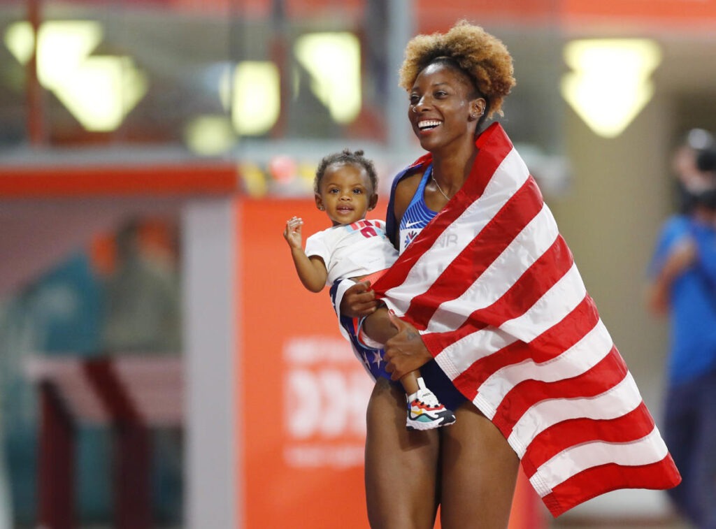Ali holds her child, while wrapped in the USA flag