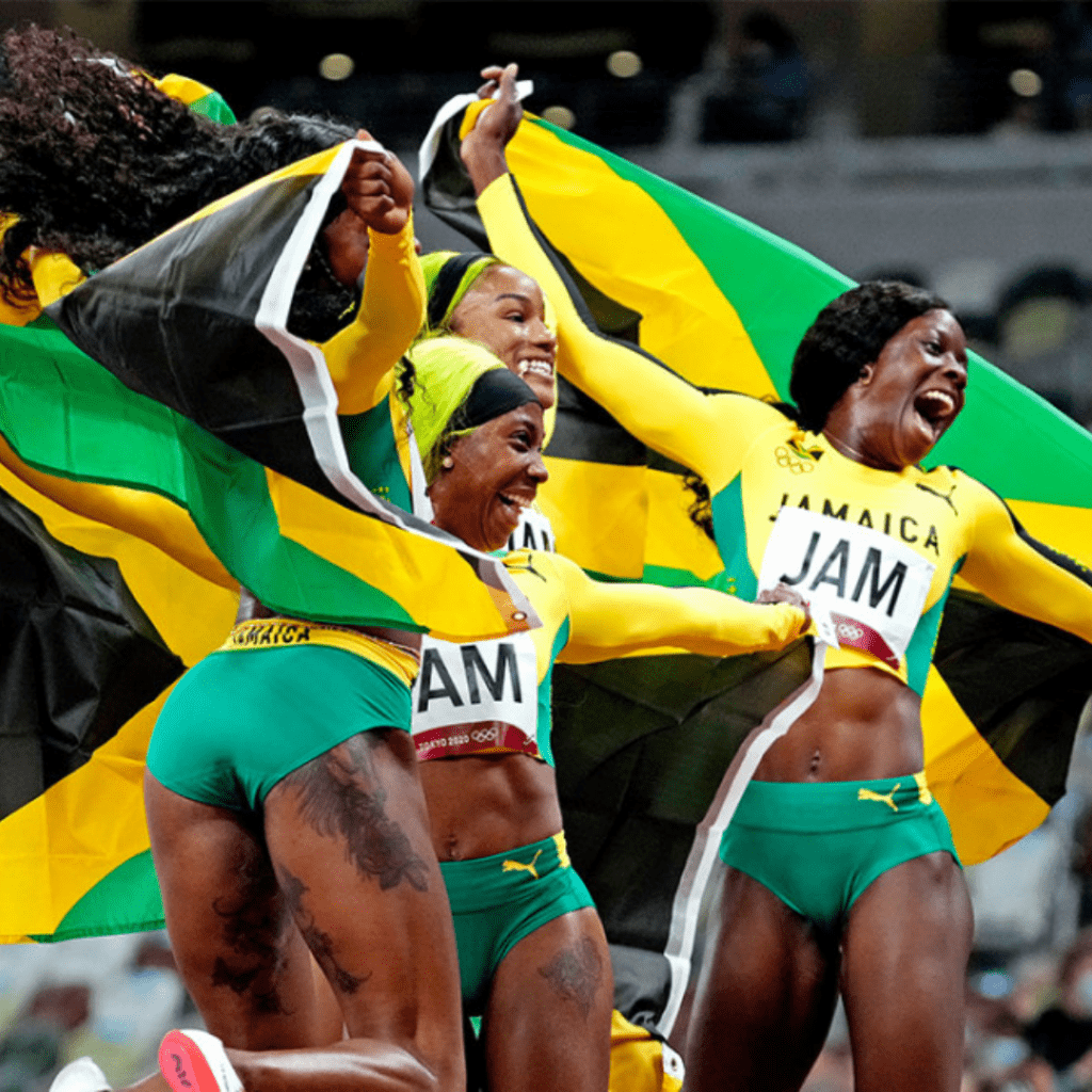 Team Jamaica jumps in the air with flags wrapped around them